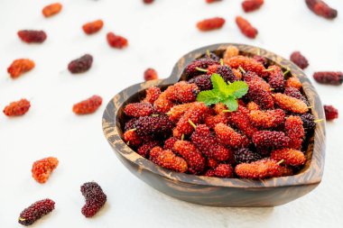 Kırmızı ve siyah dut meyve kase beyaz taş zemin üzerine