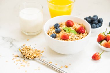 Sağlıklı kahvaltı Granola yaban mersini ve çilek ve siyah kahve, süt ve portakal suyu ile beyaz taş tablo arka planı ayarla