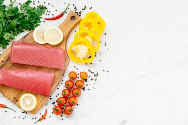 Sebze ve yemek pişirmek için madde ile ahşap kesme tahtası üzerinde ham ton balığı filetosu et