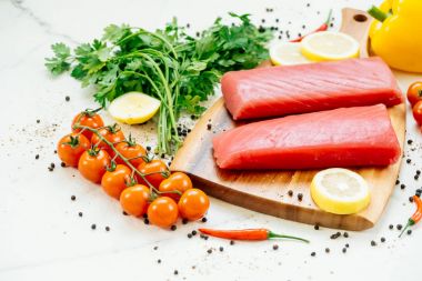 Sebze ve yemek pişirmek için madde ile ahşap kesme tahtası üzerinde ham ton balığı filetosu et