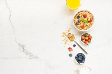Sağlıklı kahvaltı Granola yaban mersini ve çilek ve siyah kahve, süt ve portakal suyu ile beyaz taş tablo arka planı ayarla