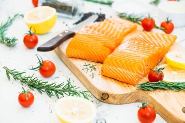 Limon domates ve diğer madde - sağlıklı gıda tarzı ahşap kesme tahtası üzerinde ham ve taze somon eti fileto