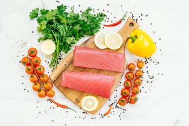 Sebze ve yemek pişirmek için madde ile ahşap kesme tahtası üzerinde ham ton balığı filetosu et