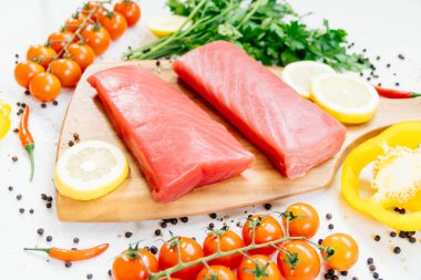 Sebze ve yemek pişirmek için madde ile ahşap kesme tahtası üzerinde ham ton balığı filetosu et