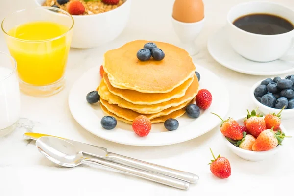 Healthy Breakfast set with Pancake and Granola with blueberry and strawberry and black coffee , Milk and Orange juice on white stone table background