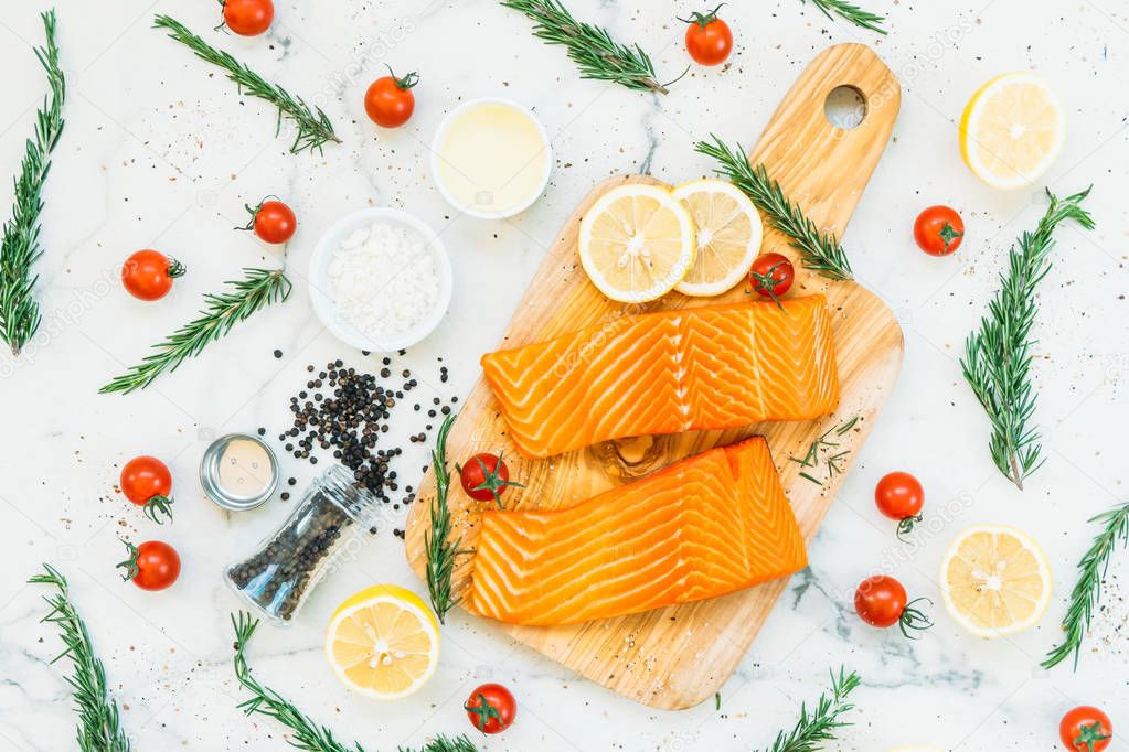 Raw and fresh salmon meat fillet on wooden cutting board with lemon tomato and other ingredient - Healthy food style