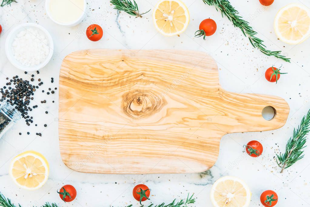 Empty wooden cutting board with copy space and lemon tomato and other ingredients