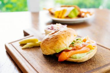 Simit ekmek ile füme somon et ve sebze ahşap kesme tahtası üzerinde