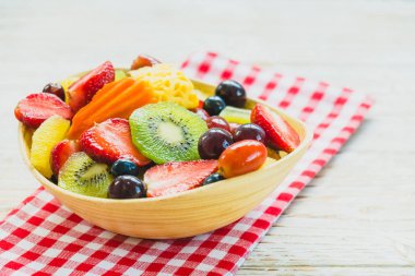 Kivi çilek üzüm ve diğer ahşap masa - filtre işleme üzerinde kase ile karışık ve çeşitli meyve