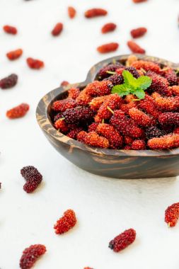 Kırmızı ve siyah dut meyve kase beyaz taş zemin üzerine