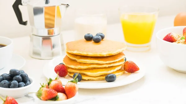 与蓝莓 草莓和黑咖啡 牛奶和橙汁在白色石头桌背景的健康早餐设置与薄饼和麦片 — 图库照片