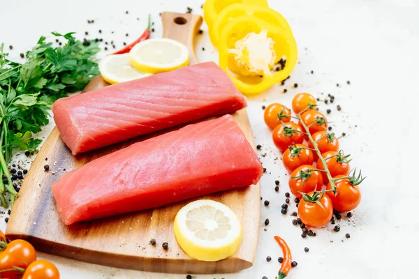 Sebze ve yemek pişirmek için madde ile ahşap kesme tahtası üzerinde ham ton balığı filetosu et