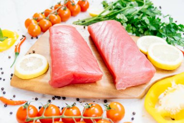 Sebze ve yemek pişirmek için madde ile ahşap kesme tahtası üzerinde ham ton balığı filetosu et