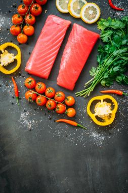 Bitkisel ve siyah taş zemin üzerine yemek için madde ile ahşap kesme tahtası üzerinde ham ton balığı filetosu et