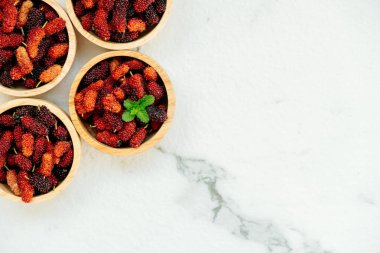 Kırmızı ve siyah dut meyve kase beyaz taş zemin üzerine