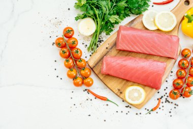 Sebze ve yemek pişirmek için madde ile ahşap kesme tahtası üzerinde ham ton balığı filetosu et