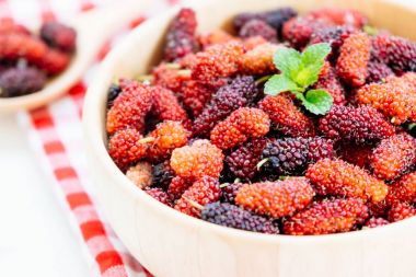 Kırmızı ve siyah dut meyve kase beyaz taş zemin üzerine