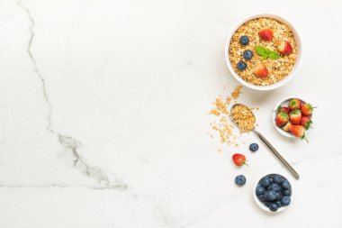 Sağlıklı kahvaltı Granola yaban mersini ve çilek ve siyah kahve, süt ve portakal suyu ile beyaz taş tablo arka planı ayarla