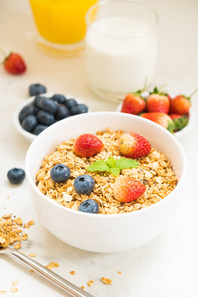 Healthy Breakfast set Granola with blueberry and strawberry and black coffee , Milk and Orange juice on white stone table background