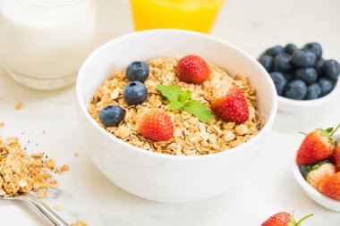 Sağlıklı kahvaltı Granola yaban mersini ve çilek ve siyah kahve, süt ve portakal suyu ile beyaz taş tablo arka planı ayarla