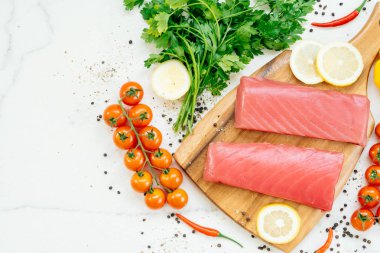 Sebze ve yemek pişirmek için madde ile ahşap kesme tahtası üzerinde ham ton balığı filetosu et