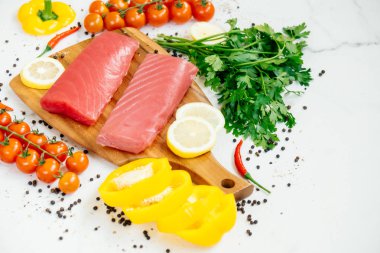 Sebze ve yemek pişirmek için madde ile ahşap kesme tahtası üzerinde ham ton balığı filetosu et