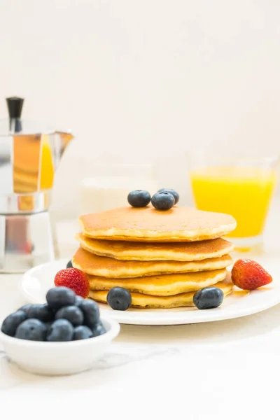 Healthy Breakfast set with Pancake and Granola with blueberry and strawberry and black coffee , Milk and Orange juice on white stone table background