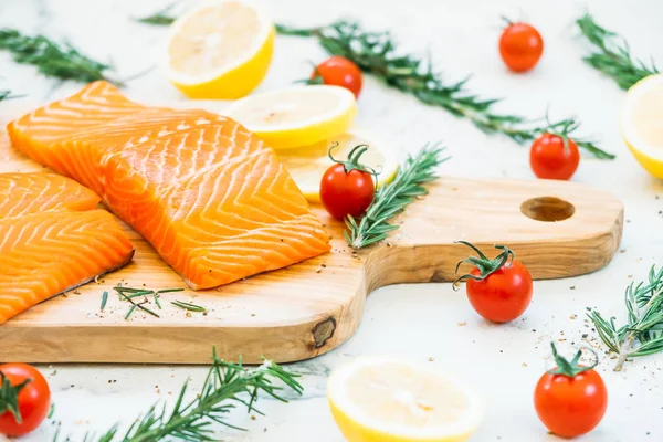 Limon domates ve diğer madde - sağlıklı gıda tarzı ahşap kesme tahtası üzerinde ham ve taze somon eti fileto