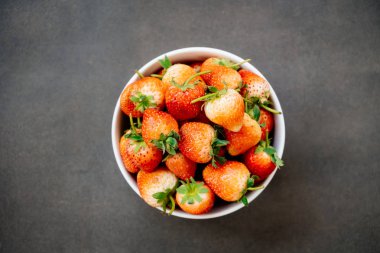 Siyah taş zemin üzerine beyaz kase çilek meyve