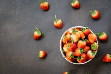 Siyah taş zemin üzerine beyaz kase çilek meyve