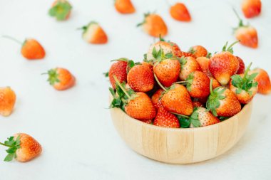 Beyaz taş zemin üzerine ahşap kase çilek meyve