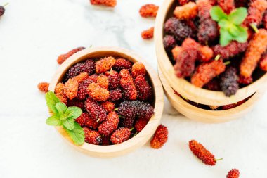 Kırmızı ve siyah dut meyve kase beyaz taş zemin üzerine