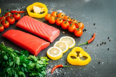 Bitkisel ve siyah taş zemin üzerine yemek için madde ile ahşap kesme tahtası üzerinde ham ton balığı filetosu et