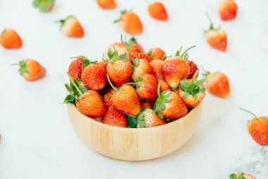 Beyaz taş zemin üzerine ahşap kase çilek meyve