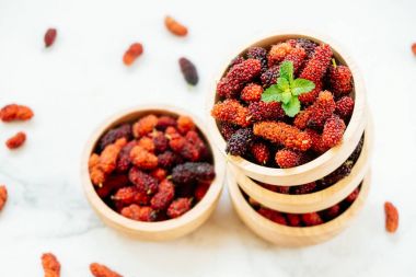 Kırmızı ve siyah dut meyve kase beyaz taş zemin üzerine