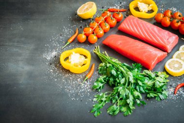 Bitkisel ve siyah taş zemin üzerine yemek için madde ile ahşap kesme tahtası üzerinde ham ton balığı filetosu et