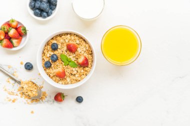 Sağlıklı kahvaltı Granola yaban mersini ve çilek ve siyah kahve, süt ve portakal suyu ile beyaz taş tablo arka planı ayarla