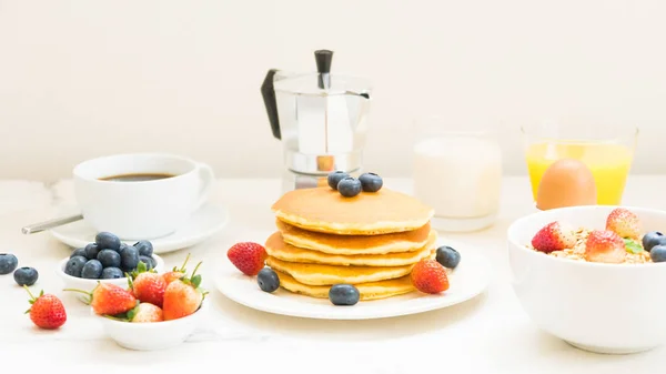 与蓝莓 草莓和黑咖啡 牛奶和橙汁在白色石头桌背景的健康早餐设置与薄饼和麦片 — 图库照片