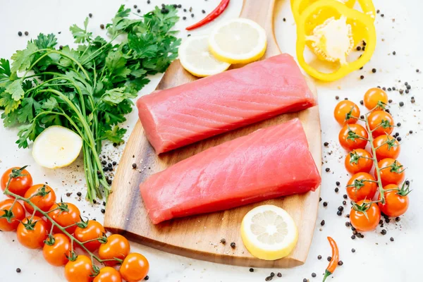 Sebze ve yemek pişirmek için madde ile ahşap kesme tahtası üzerinde ham ton balığı filetosu et