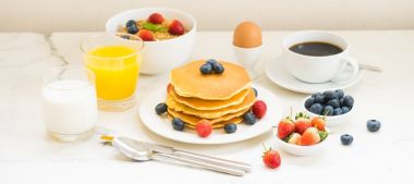 Sağlıklı kahvaltı kümesiyle gözleme ve Granola yaban mersini ve çilek ve siyah kahve, süt ve portakal suyu beyaz taş masa arka plan