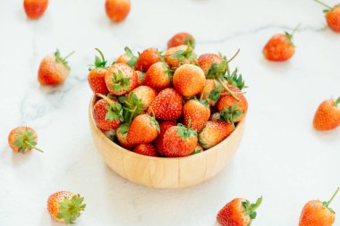 Beyaz taş zemin üzerine ahşap kase çilek meyve