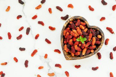 Kırmızı ve siyah dut meyve kase beyaz taş zemin üzerine