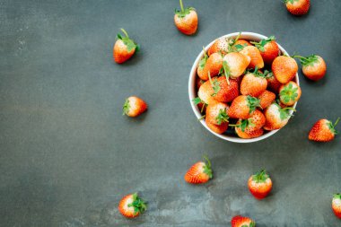 Siyah taş zemin üzerine beyaz kase çilek meyve