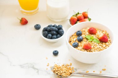 Sağlıklı kahvaltı Granola yaban mersini ve çilek ve siyah kahve, süt ve portakal suyu ile beyaz taş tablo arka planı ayarla