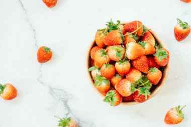 Beyaz taş zemin üzerine ahşap kase çilek meyve