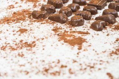 Şekerli tatlı koyu çikolata parçaları ve beyaz taş zemin üzerine kakao tozu