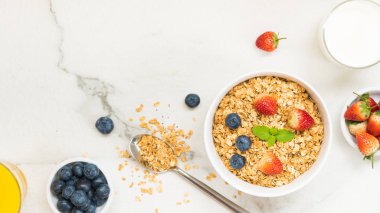 Sağlıklı kahvaltı Granola yaban mersini ve çilek ve siyah kahve, süt ve portakal suyu ile beyaz taş tablo arka planı ayarla