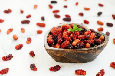 Kırmızı ve siyah dut meyve kase beyaz taş zemin üzerine