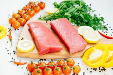 Sebze ve yemek pişirmek için madde ile ahşap kesme tahtası üzerinde ham ton balığı filetosu et