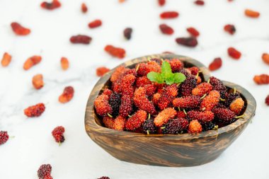 Kırmızı ve siyah dut meyve kase beyaz taş zemin üzerine